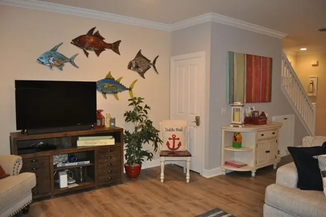 Living area with colorful metal fish wall art, an Indigo Reef anchor chair, and stairs.