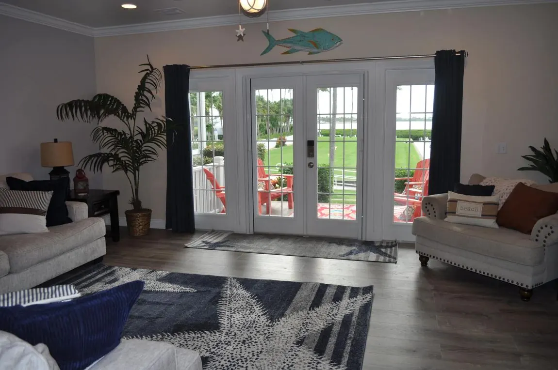 Living room with French doors to the deck, turquoise fish wall art, and a navy starfish rug.