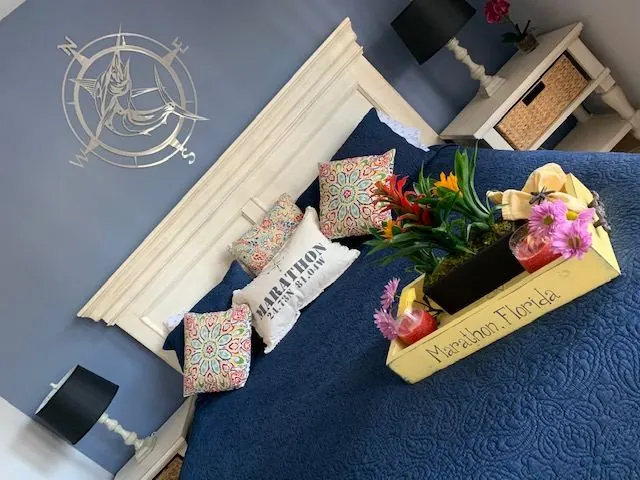 Master bedroom with navy walls, a marlin compass wall sculpture, and a navy bedspread.